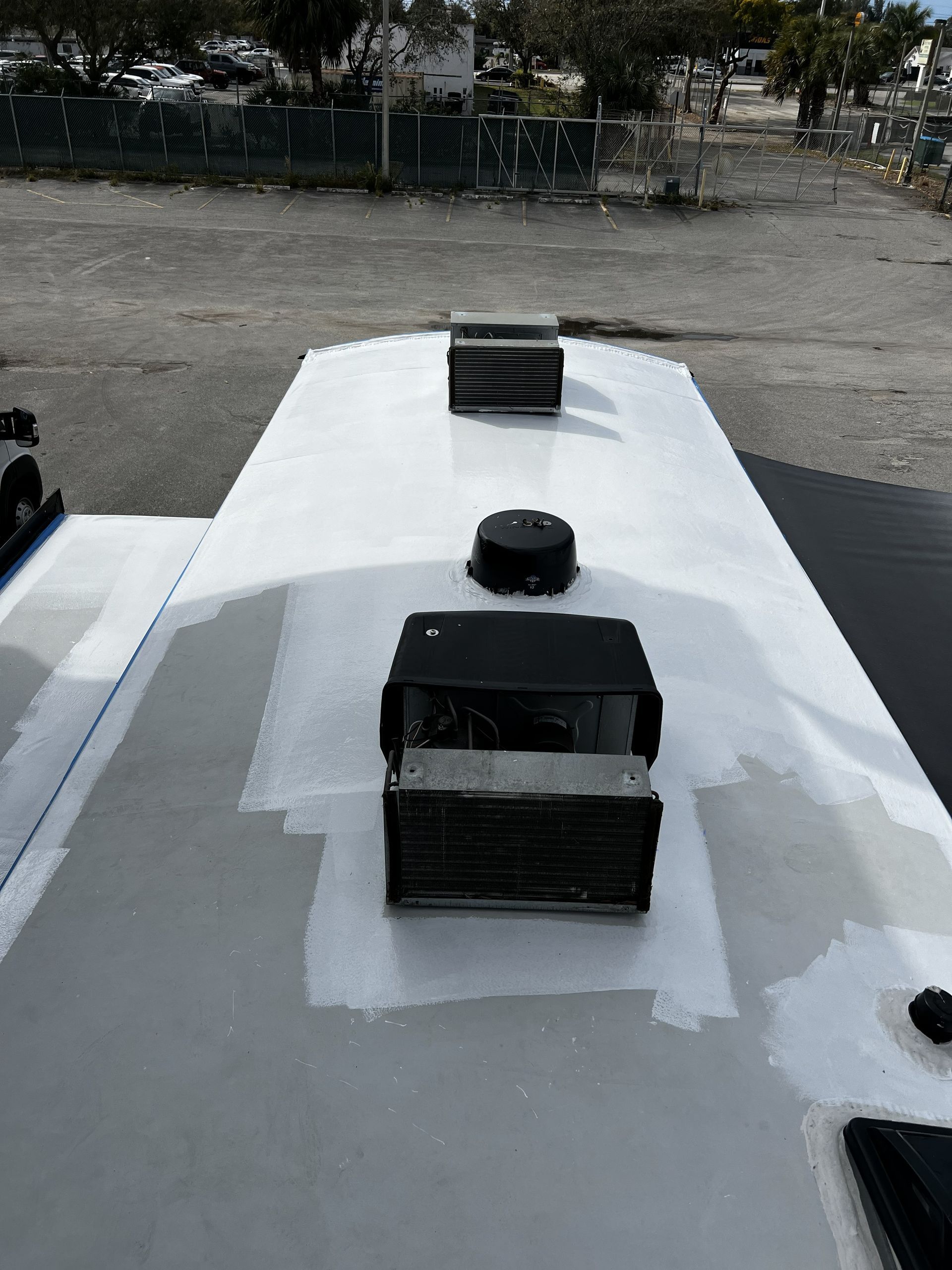 RV roof with air vents, painted gray with white patches, outdoors.