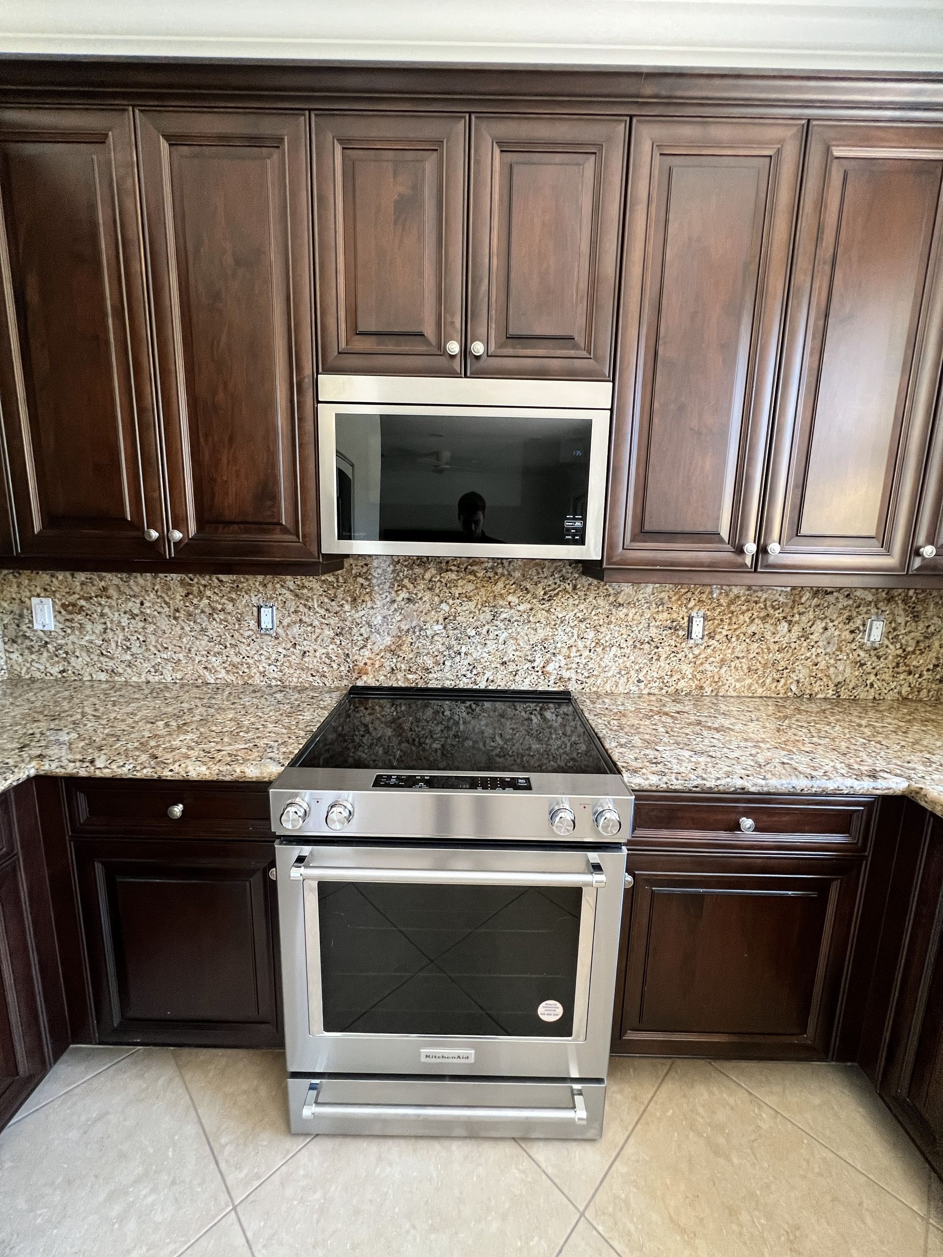 Kitchen with dark brown cabinets, granite countertops, and stainless steel oven/range.