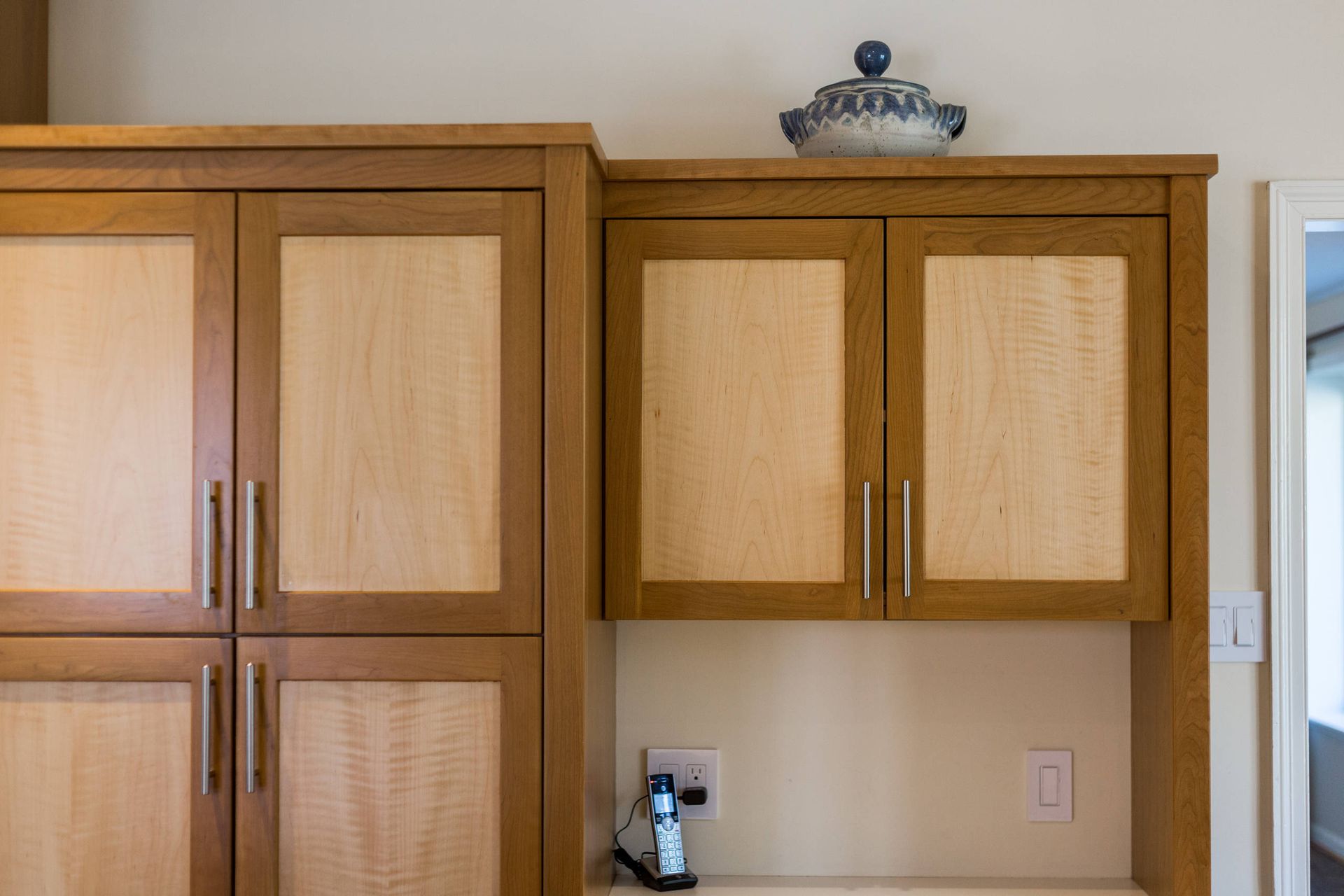 A kitchen with wooden cabinets and a telephone on the counter.
