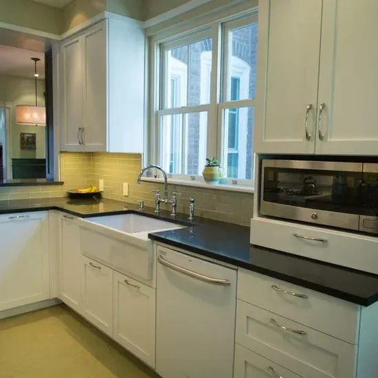 A kitchen with white cabinets a sink and a microwave