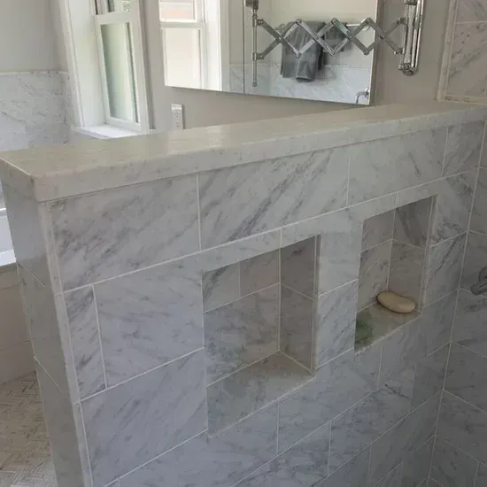 A bathroom with marble tiles and a mirror on the wall. James McCoy Remodeling Services Serving 19072,19003,19118,19444,19095 and surrounding areas