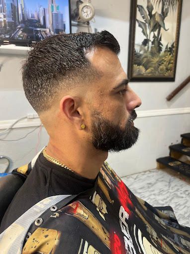 A man with a beard is getting his hair cut at a barber shop.