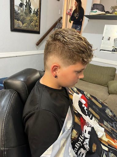A young boy is getting his hair cut at a barber shop.
