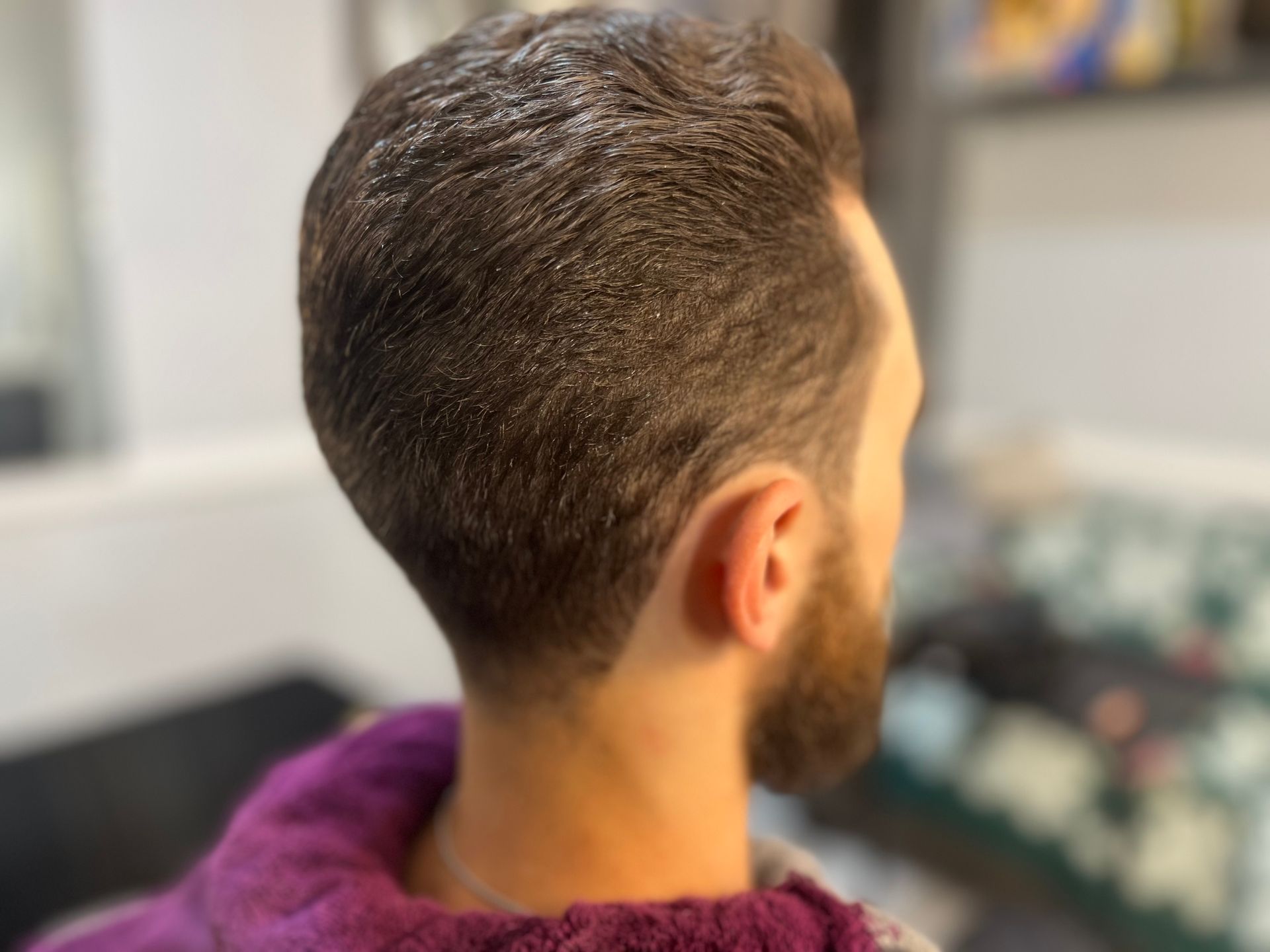 A man with a beard and short hair is wearing a purple sweater.