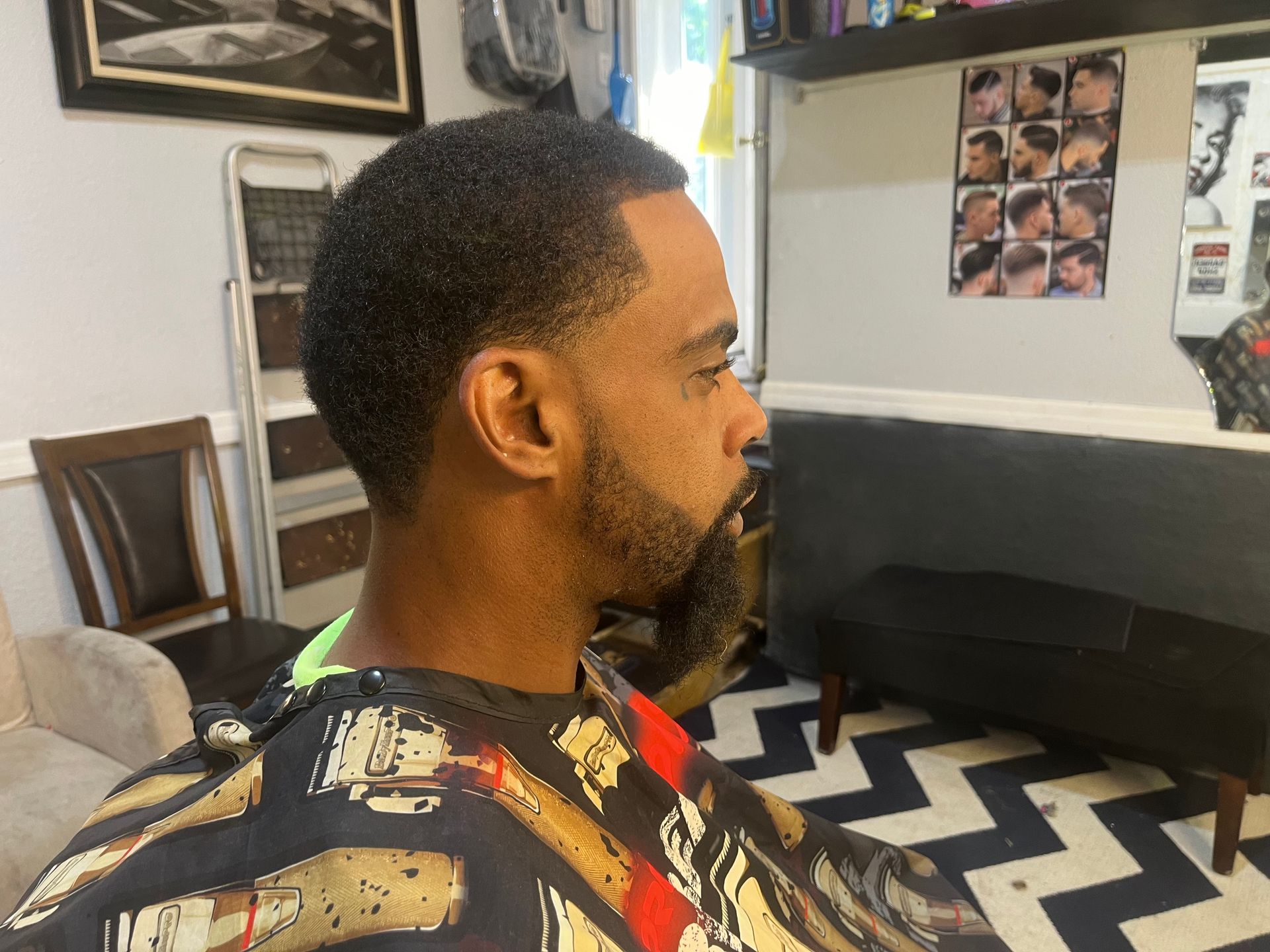 A man with a beard is getting his hair cut in a barber shop.