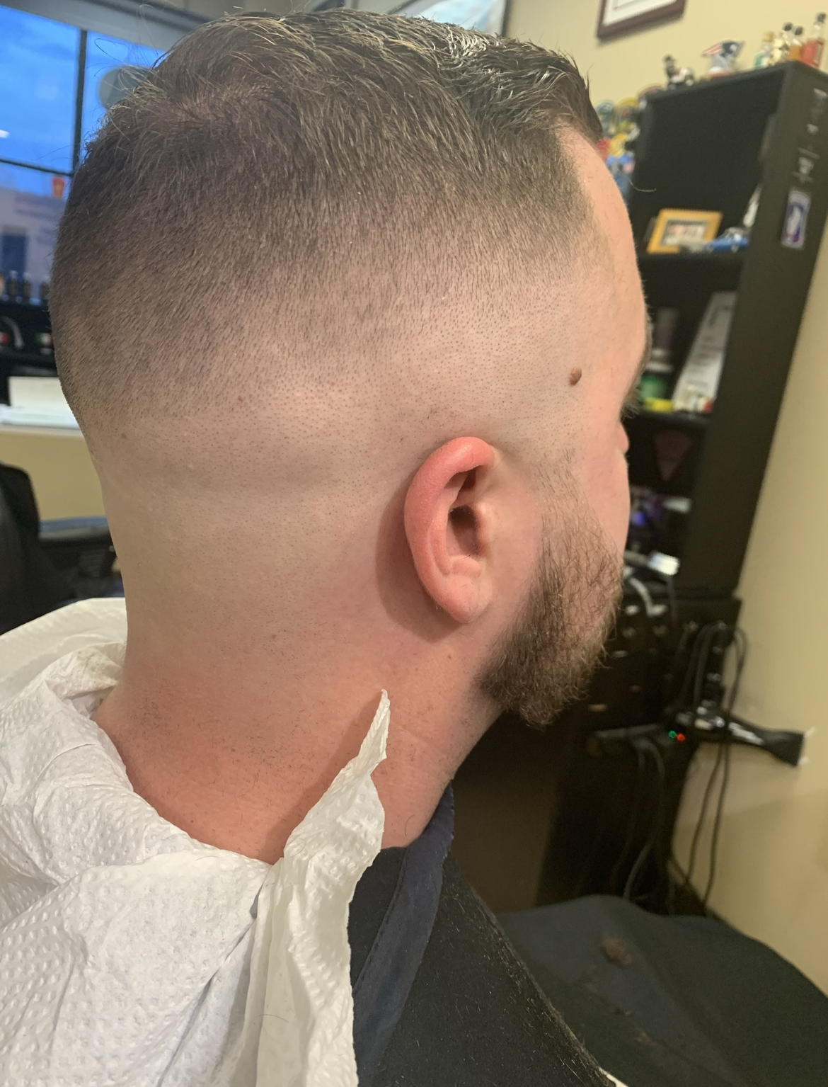A man with a beard is getting his hair cut by a barber