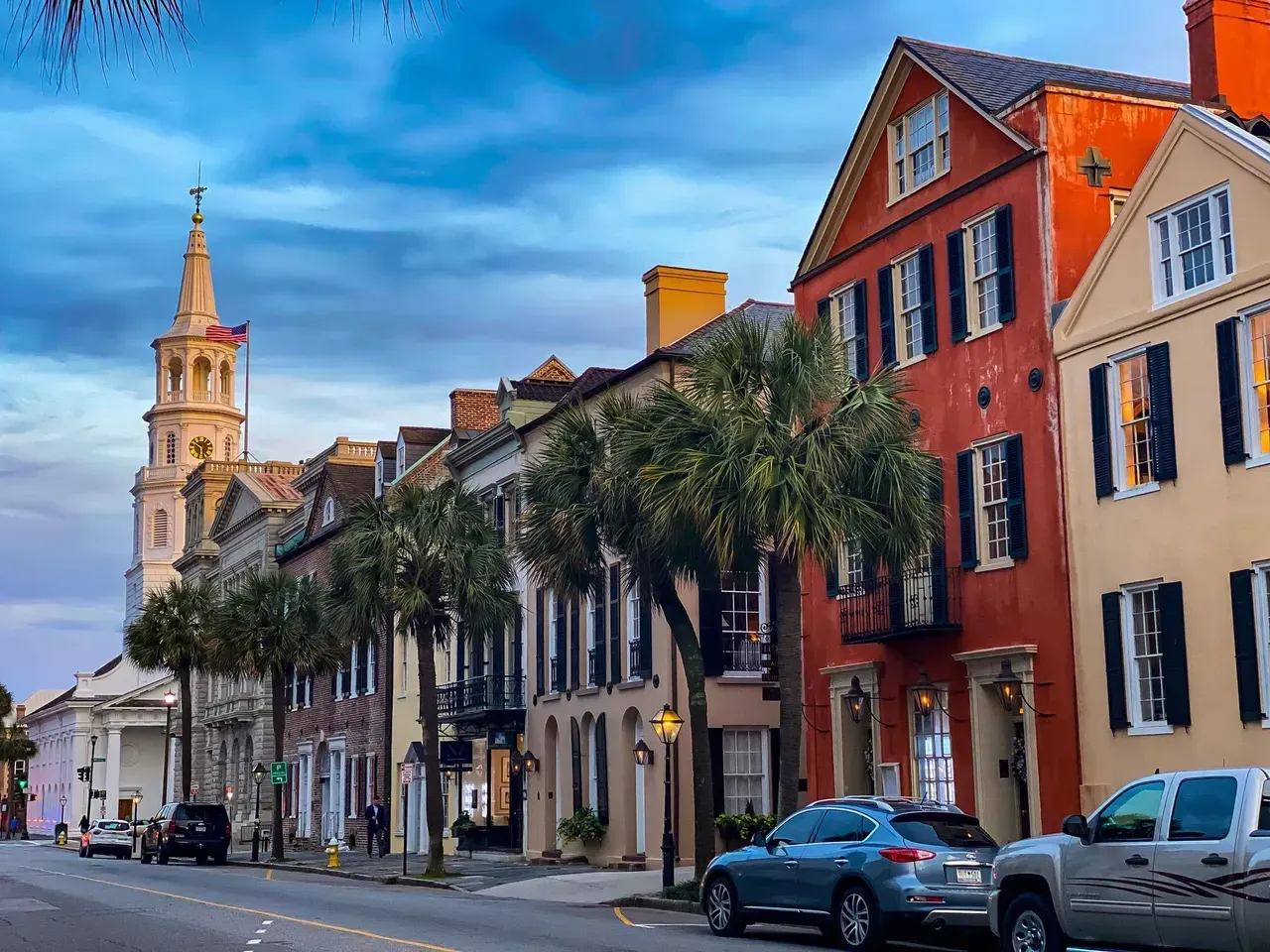 A row of buildings on a city street with a church in the background.