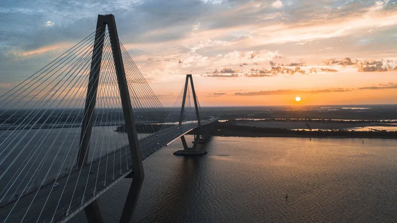 An aerial view of a bridge over a body of water at sunset.