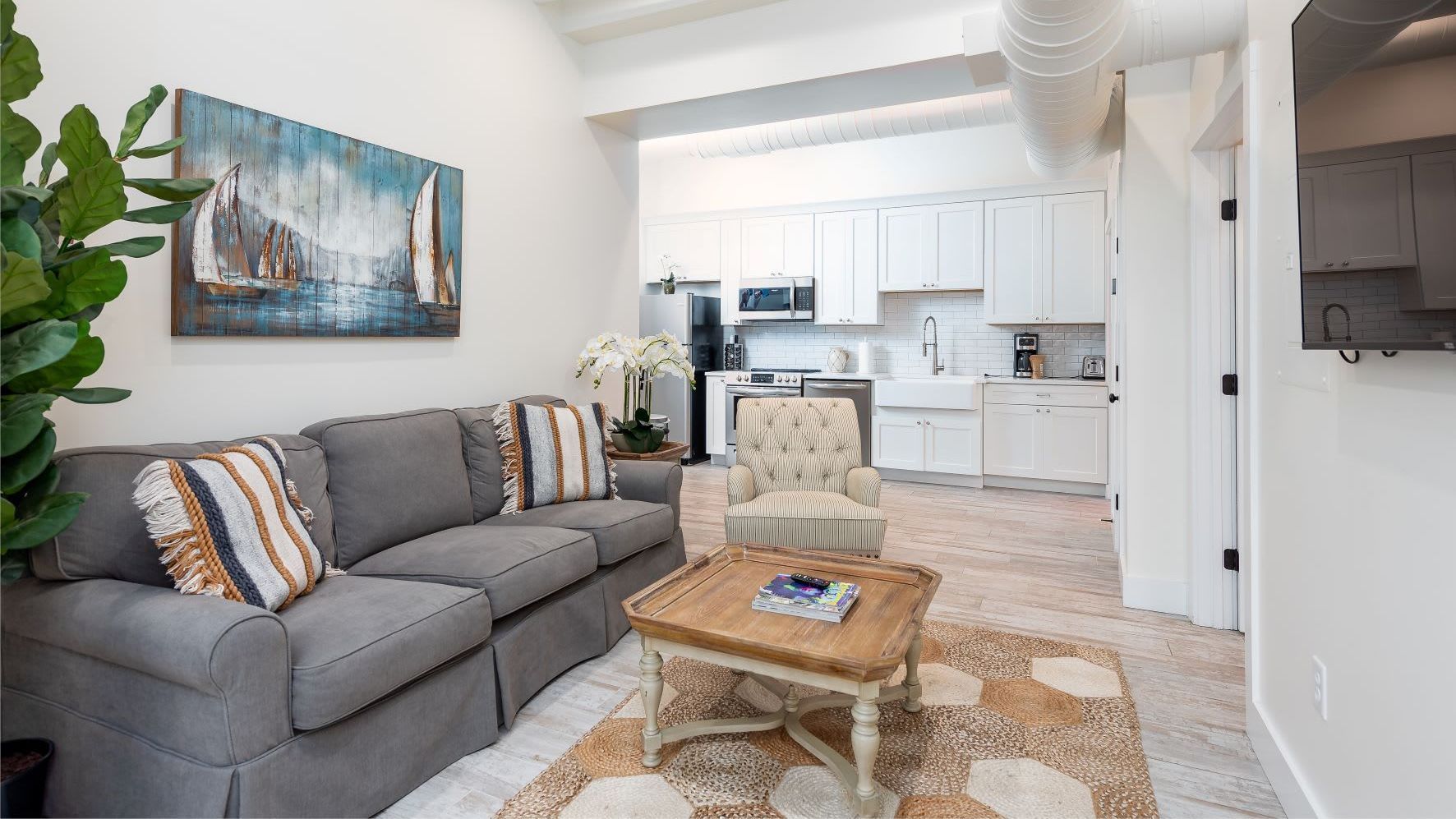 A living room with a couch , chair , coffee table and television.