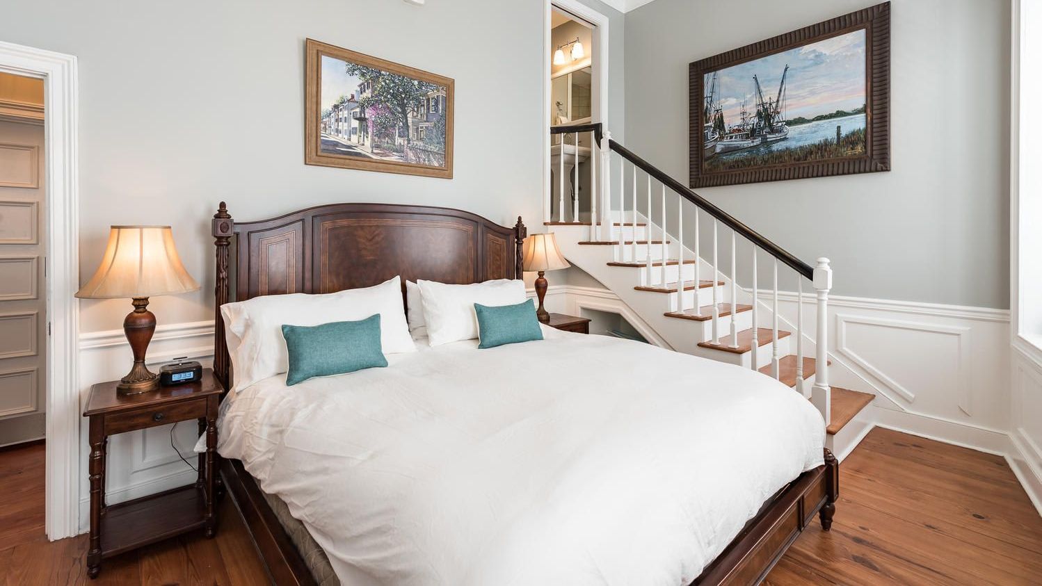 A bedroom with a large bed and stairs leading up to the second floor.