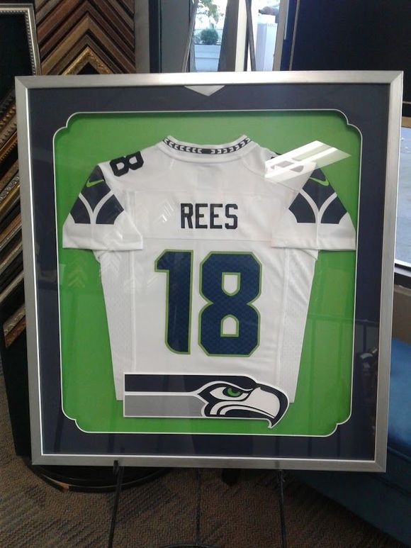 Framed Seattle Seahawks jersey. White, blue, and green. Displayed in a custom shadowbox with a green background.