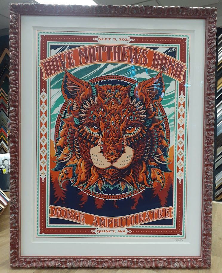 Dave Matthews Band concert poster framed in reddish brown. Features a Lynx head in orange, teal, and brown.