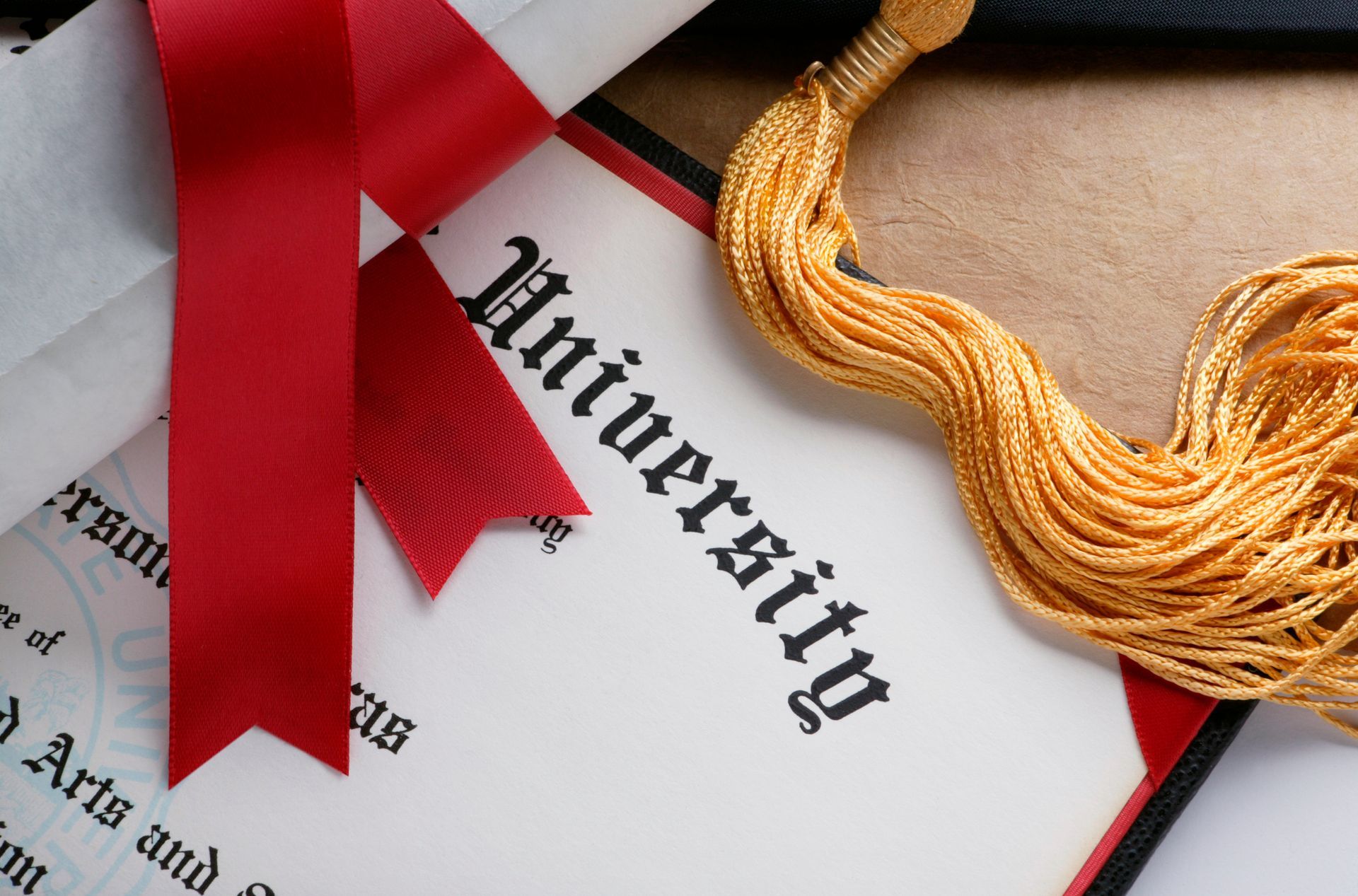 Diploma with red ribbon and gold tassel, signifying university graduation.