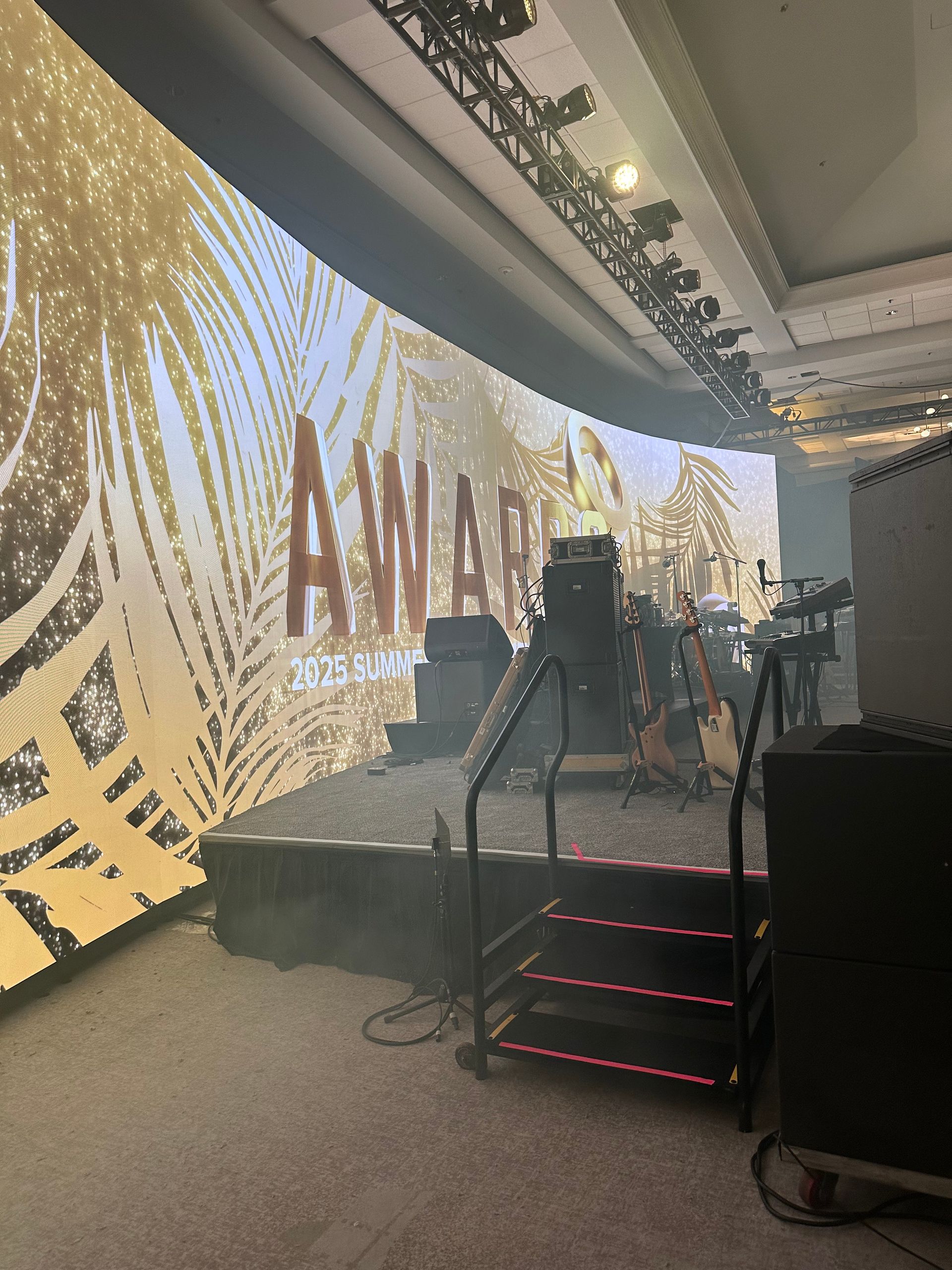 A stage setup featuring a large curved screen displaying the word