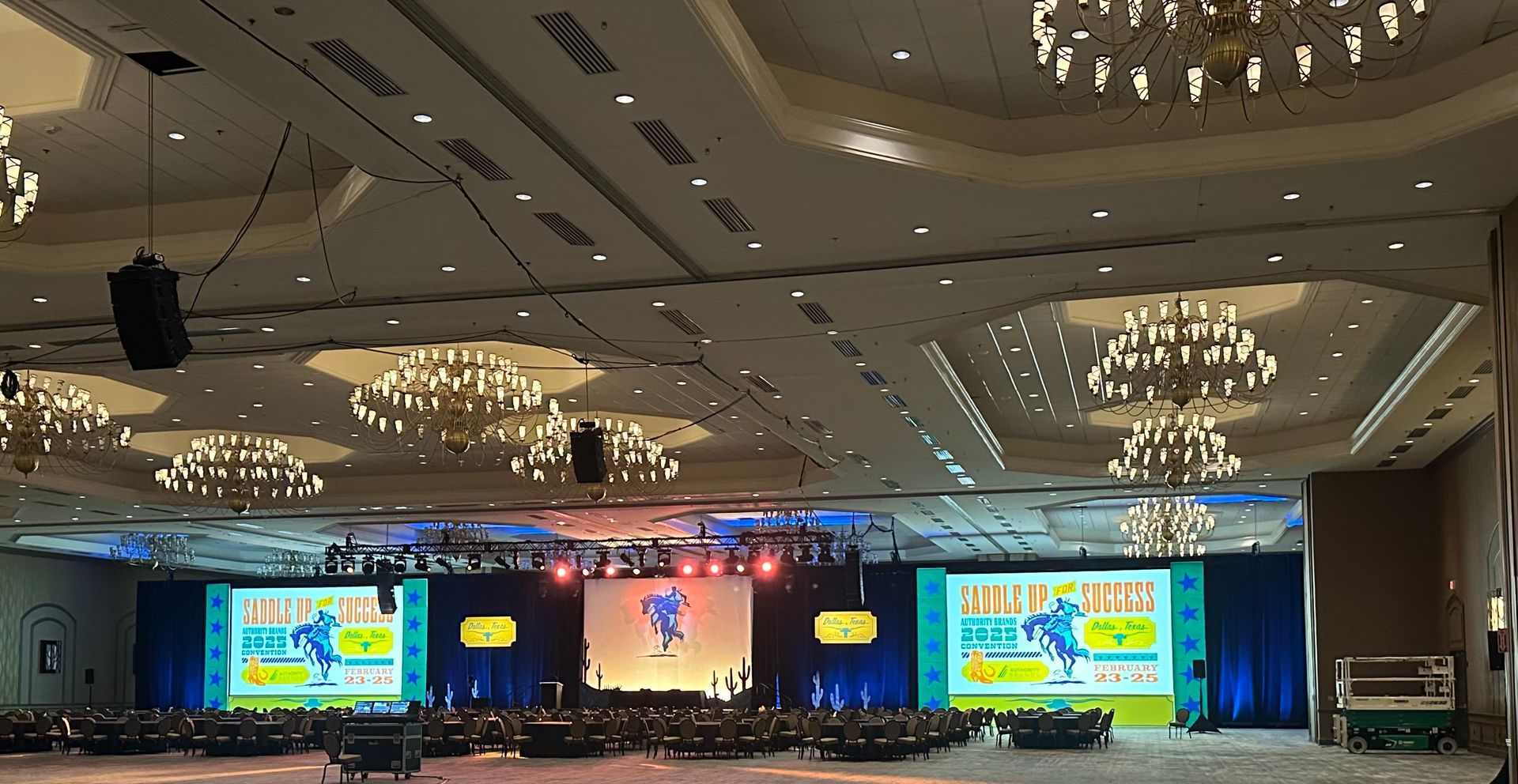 A large conference hall with three screens showing a 