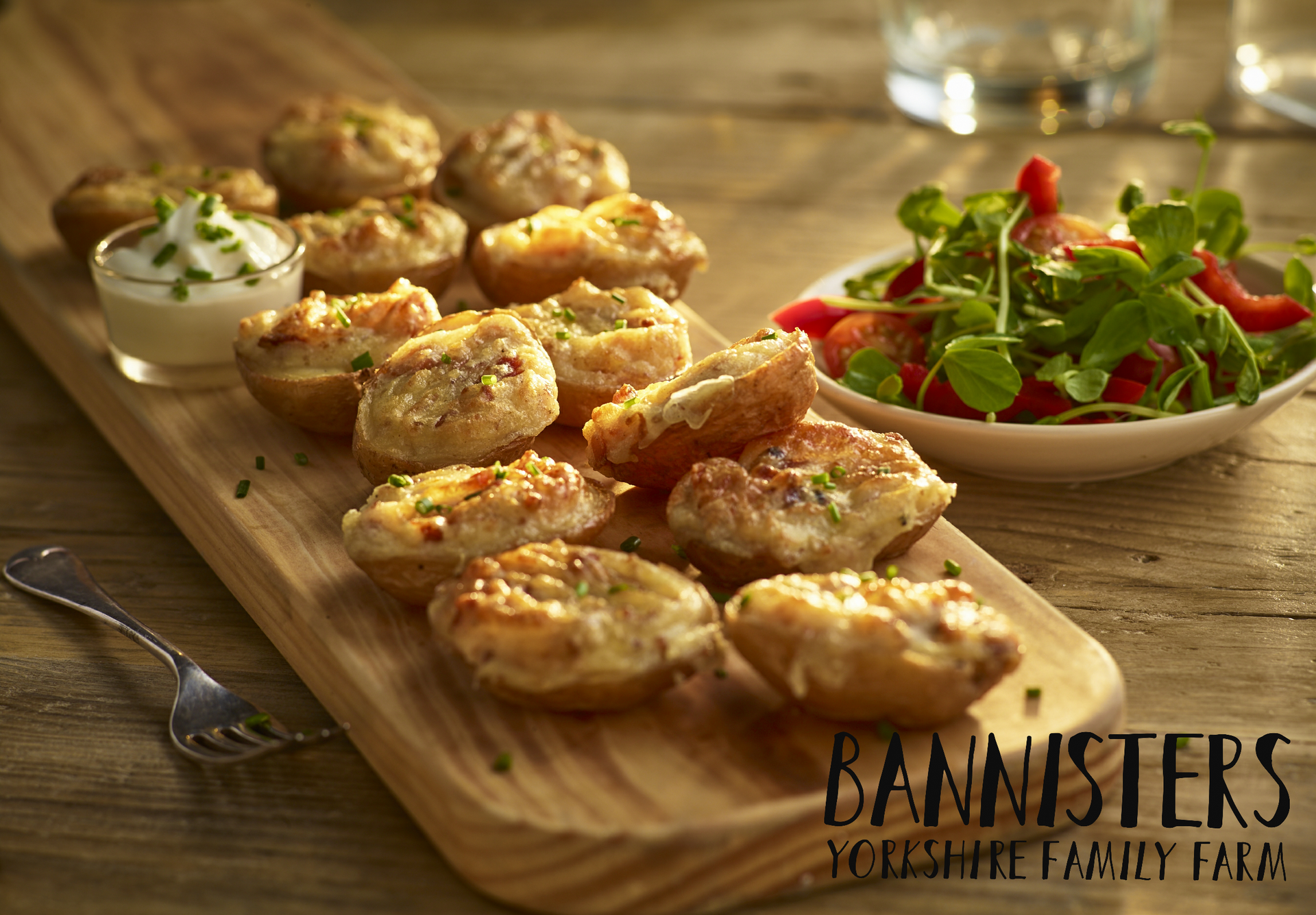 Tray of golden baked appetizers with herb garnish beside a green salad on a wooden table