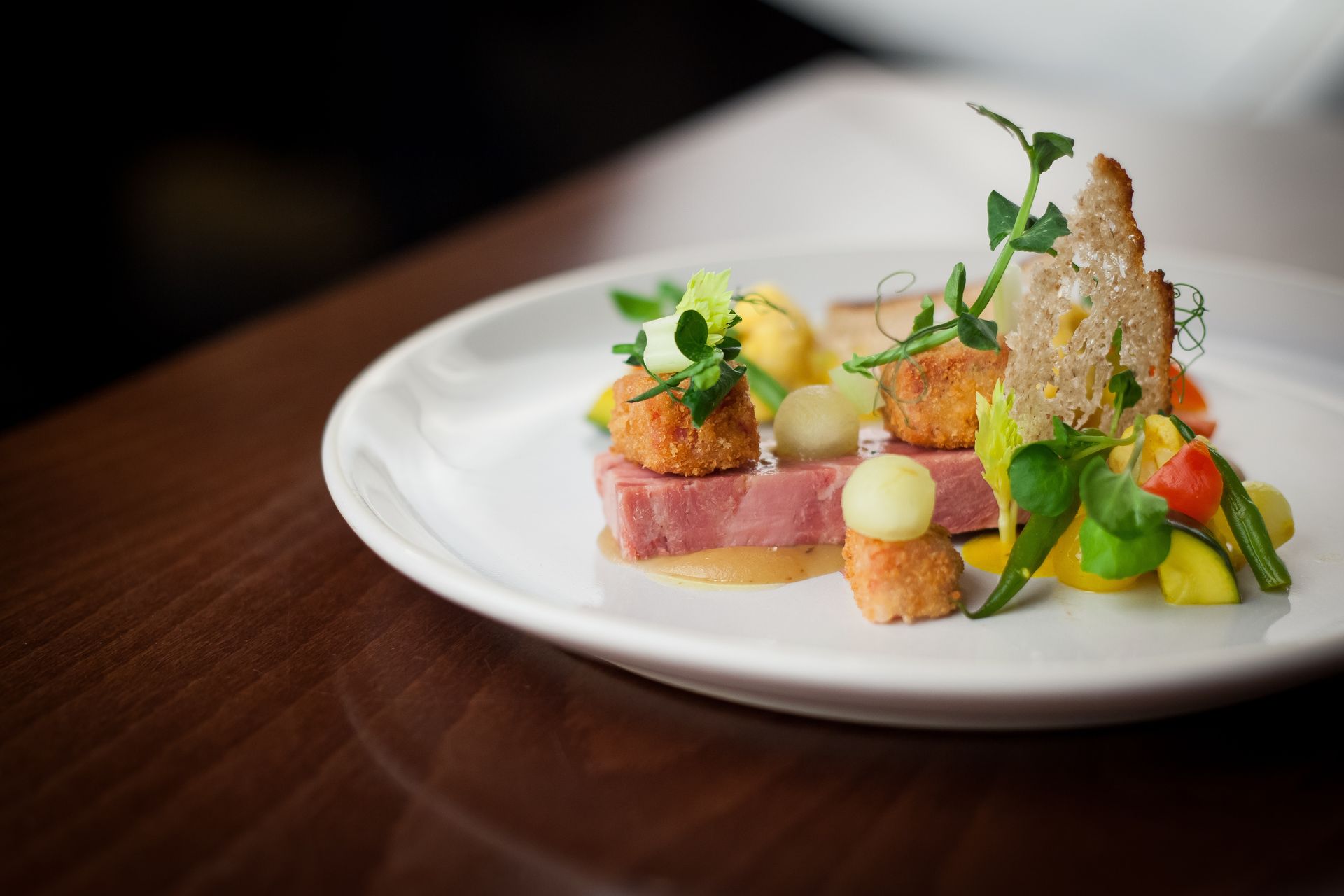 Gourmet plated dish with vegetables, herbs, and crispy garnish on a white plate