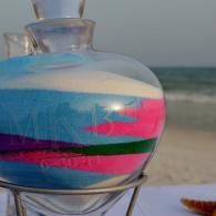 Colorful striped glass bottle on a beach with ocean and sand in the background
