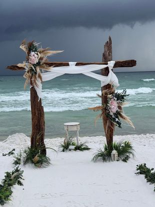 Beach wedding setup with white chairs, starfish aisle, and floral arch facing the ocean