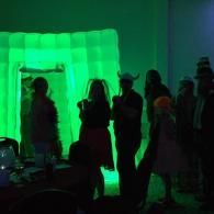 Silhouetted people standing before a glowing green backdrop at a party or performance