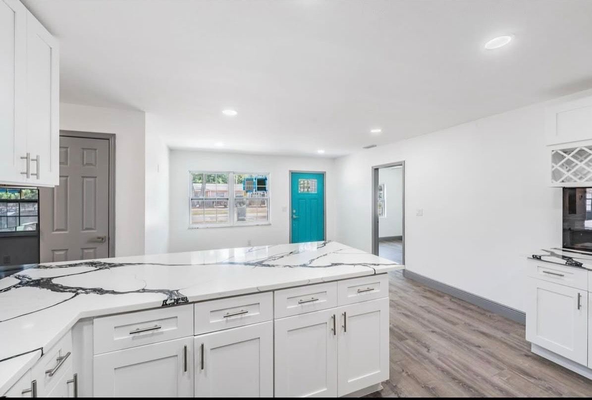 A kitchen with white cabinets , granite counter tops , and a large island.