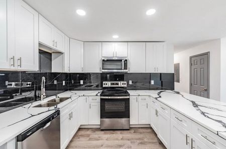 A kitchen with white cabinets and stainless steel appliances.