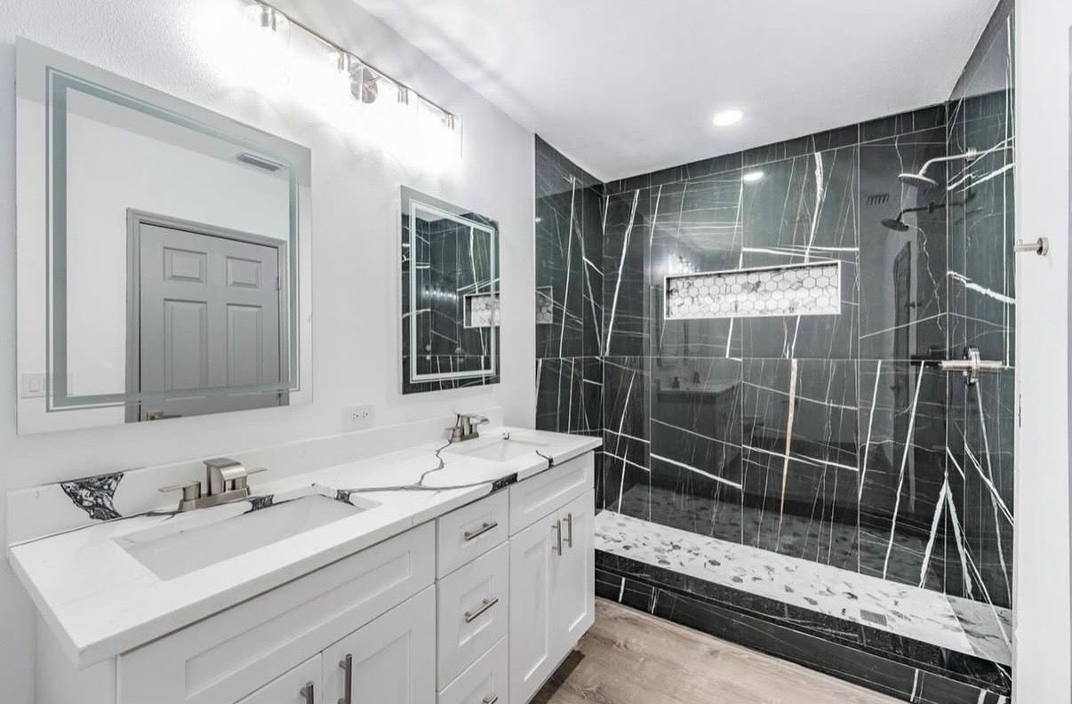 A bathroom with a sink , mirror , and walk in shower.