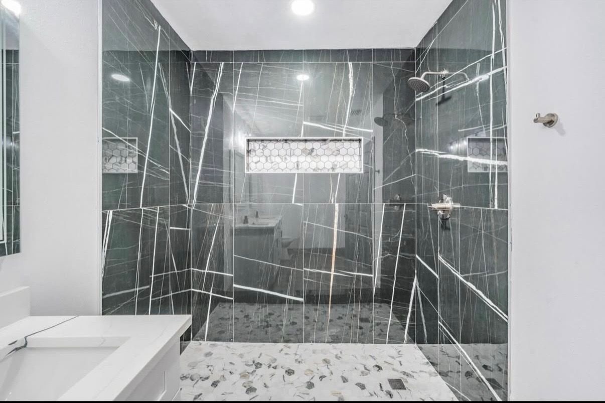 A bathroom with black and white tiles and a walk in shower.