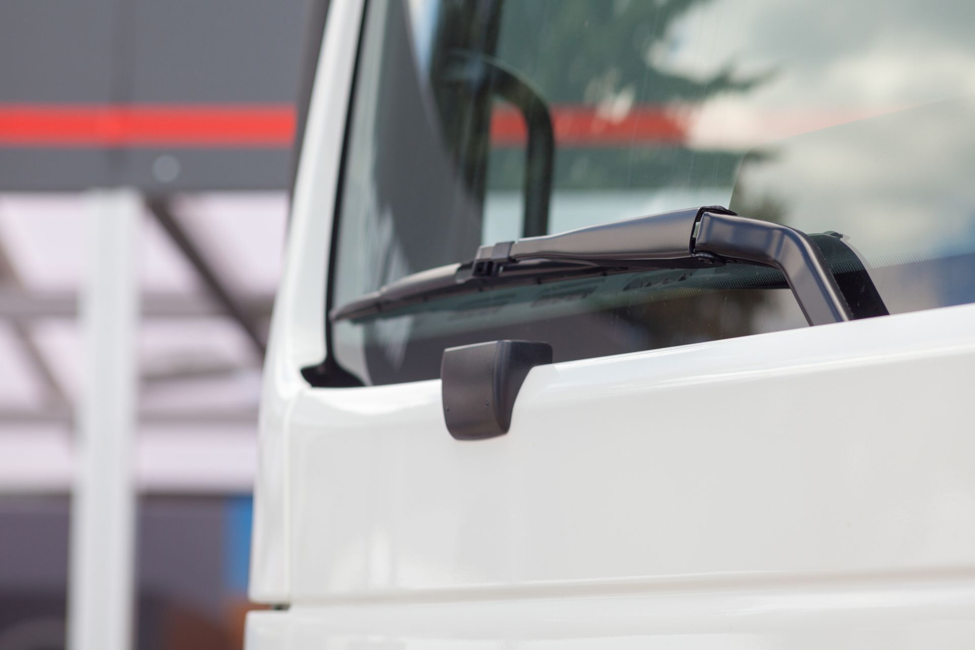 A White Truck with A Wiper on The Windshield Is Parked in Front of A Building.