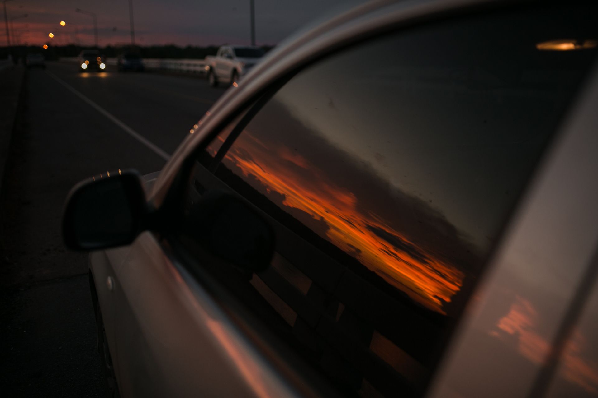 A Car Is Driving Down a Highway at Sunset.