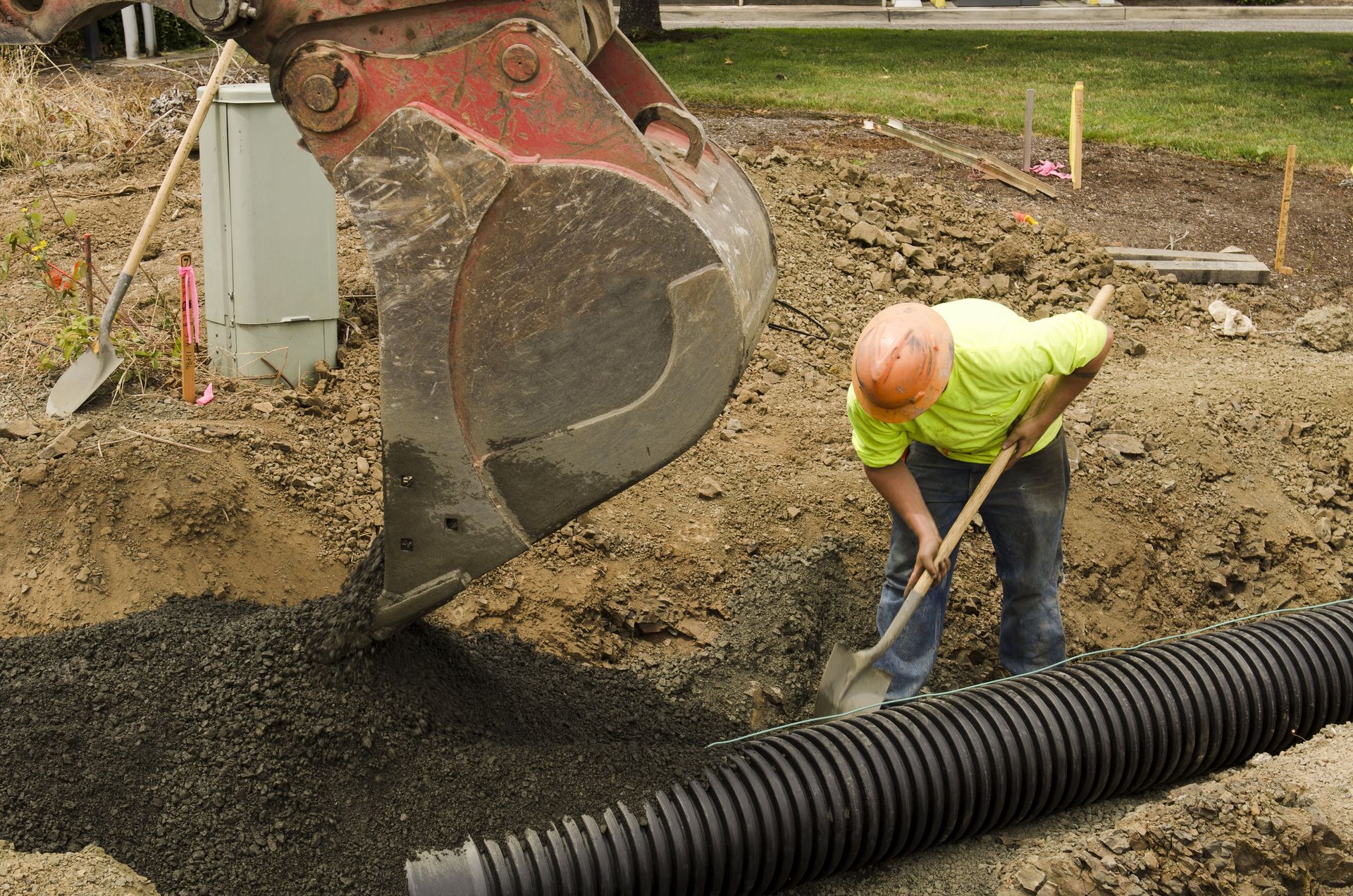 A construction worker is digging in the dirt with a shovel