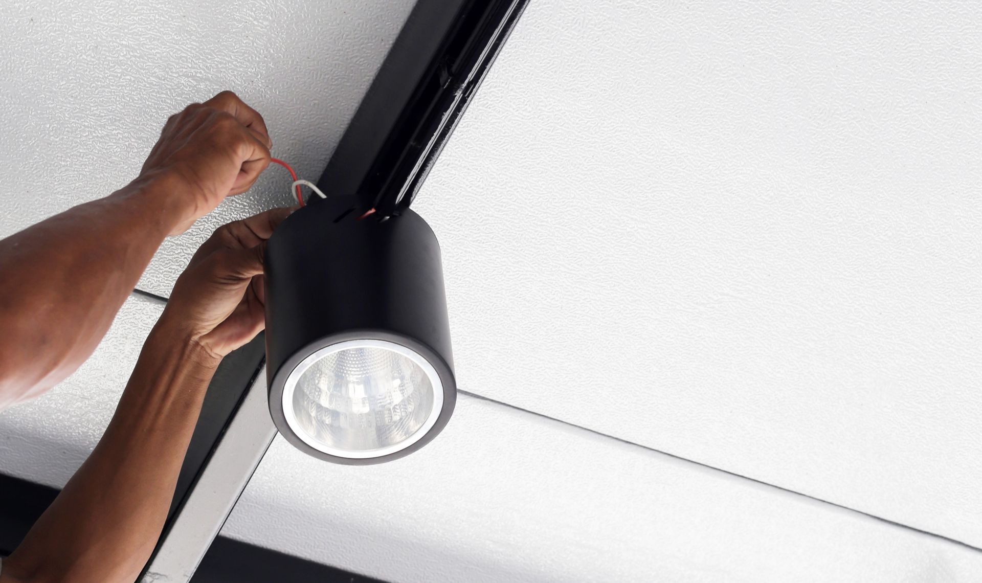 Hands of an electrician installing a light on the ceiling