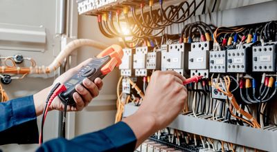 An Electrician Is Working on An Electrical Panel with A Multimeter — Dalton, GA — Dalton Service Inc