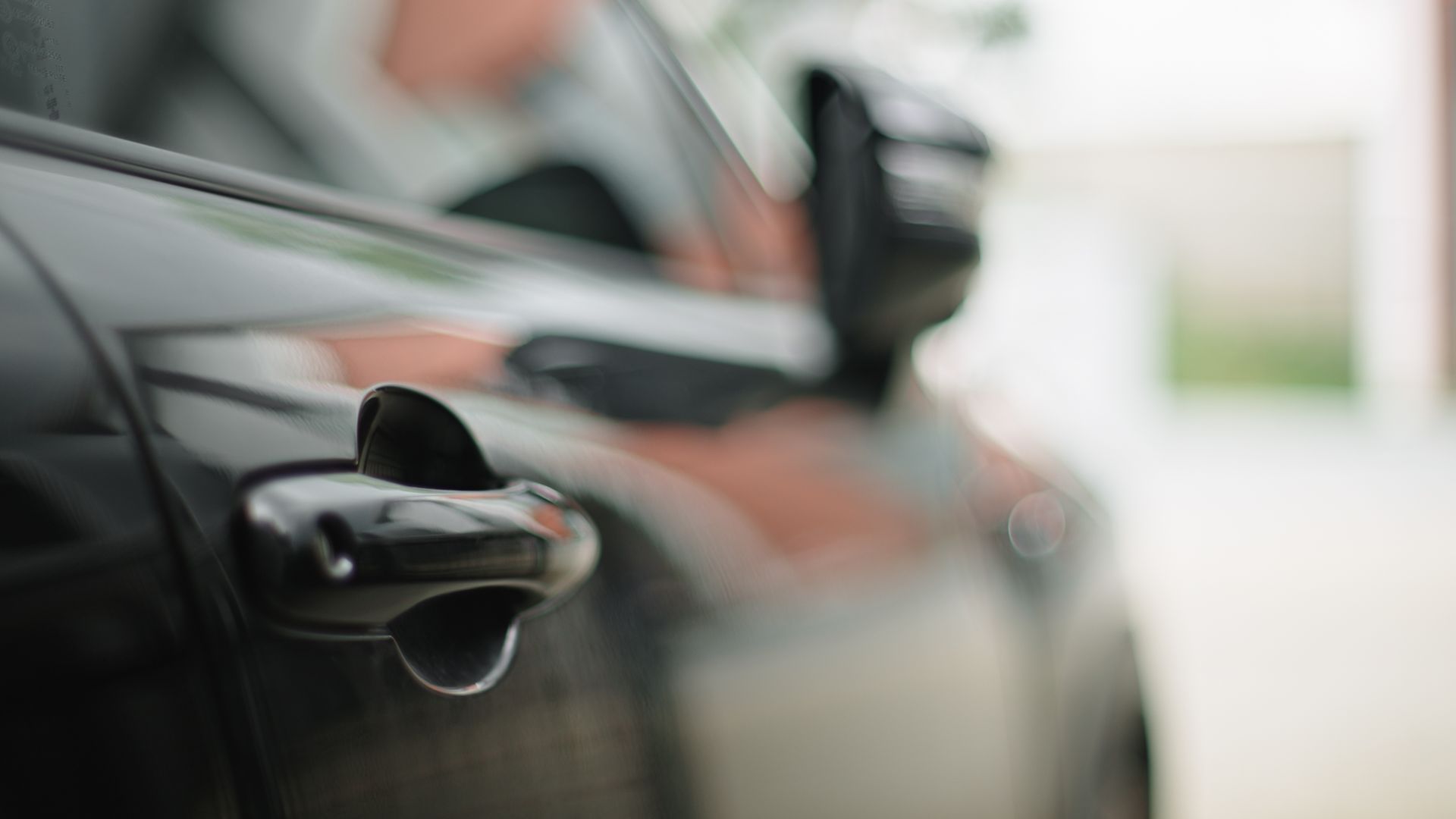 A close up of a car door handle on a black car.