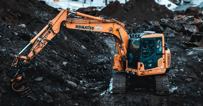 A yellow excavator is sitting on top of a pile of dirt.