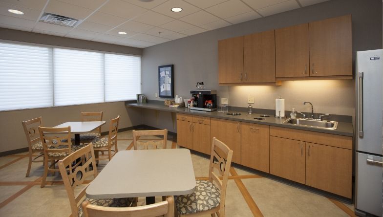 A kitchen with tables and chairs and a refrigerator