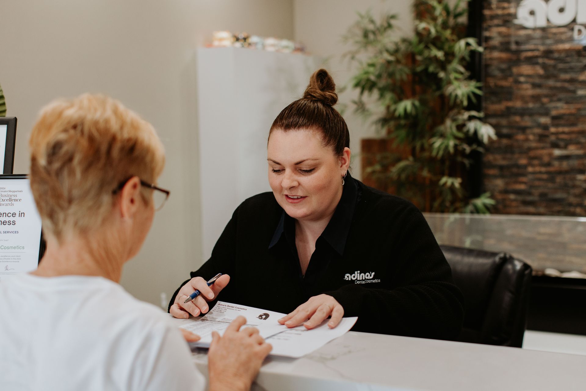 A woman is sitting at a counter talking to another woman.