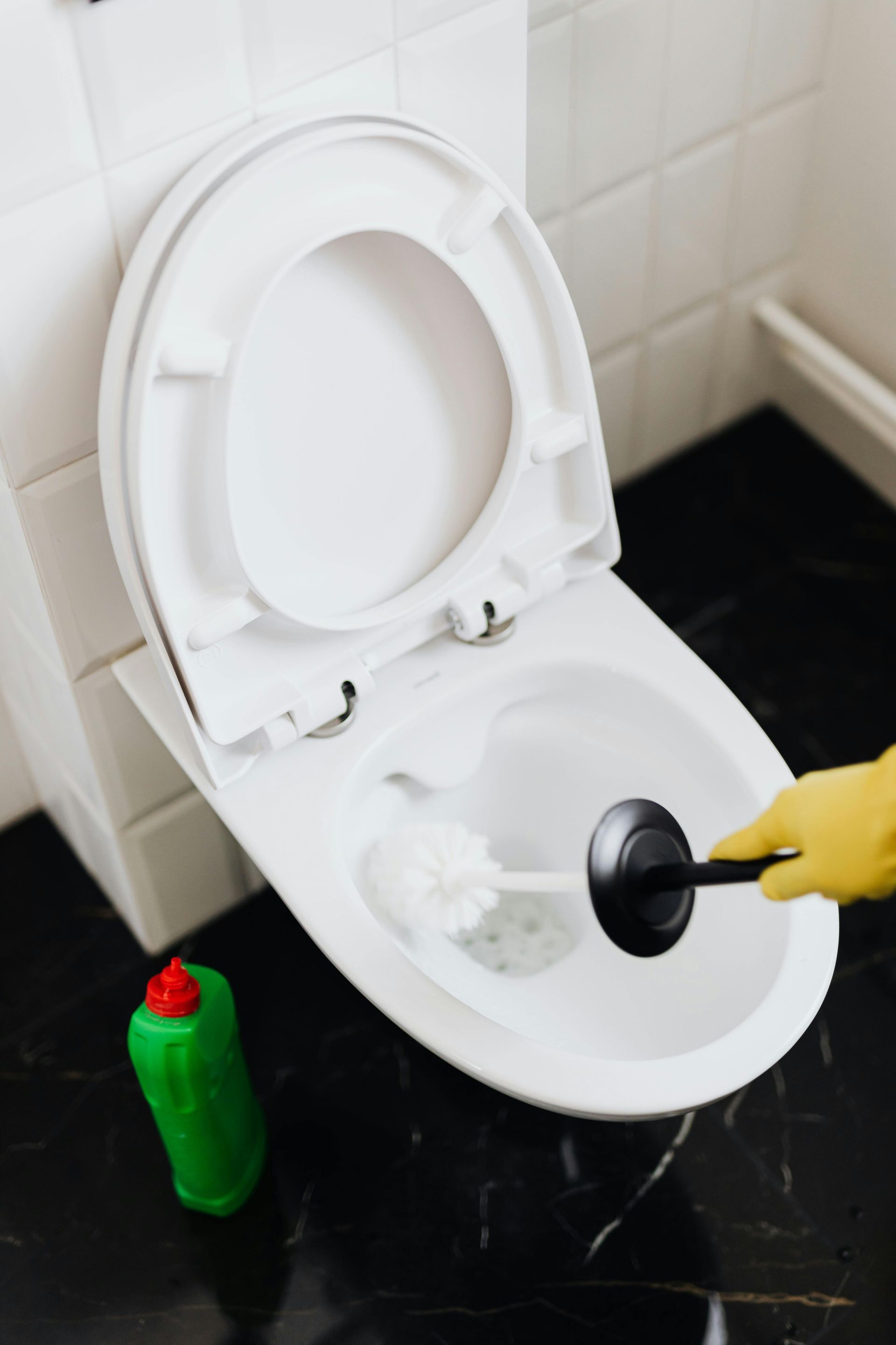 A person is cleaning a toilet with a plunger.