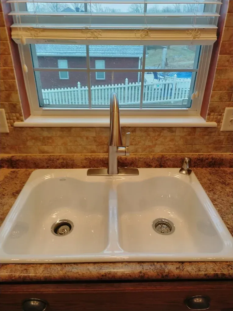Patio with cream-colored awning overlooking water, furnished with seating and fire pit.