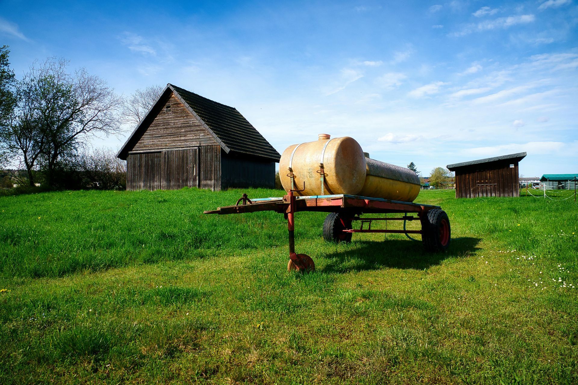 Patio with seating under a slatted pergola, overlooking a grassy backyard.