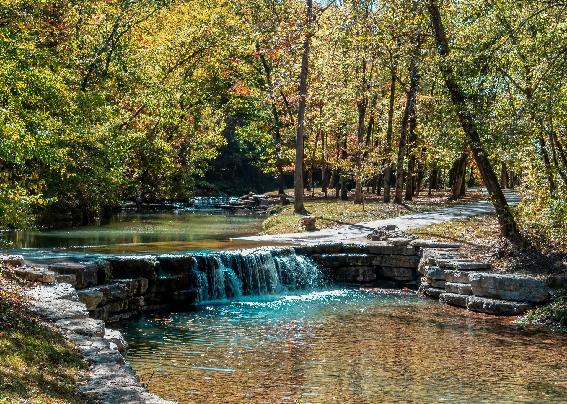 Bright blue sky with wispy clouds over a green field and a line of trees.