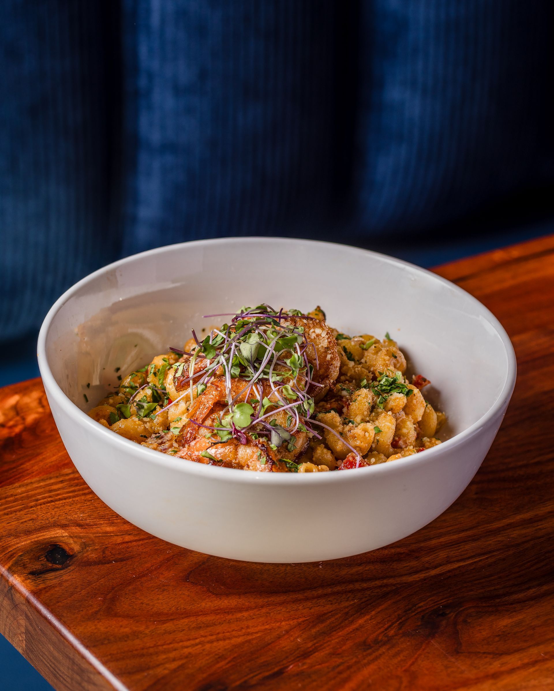 A bowl of macaroni and cheese is on a wooden table