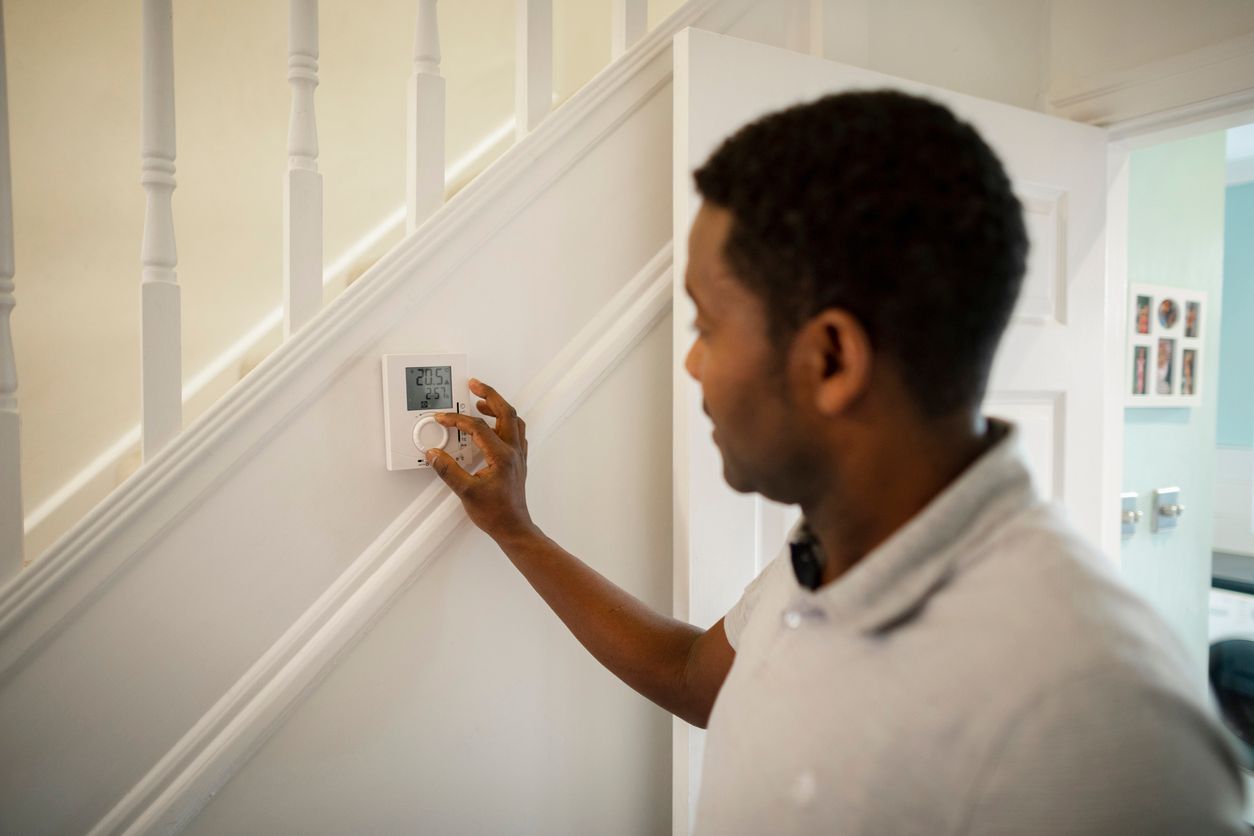 Man adjusting the temperature in his home thermostat - replacing home thermostat tips.