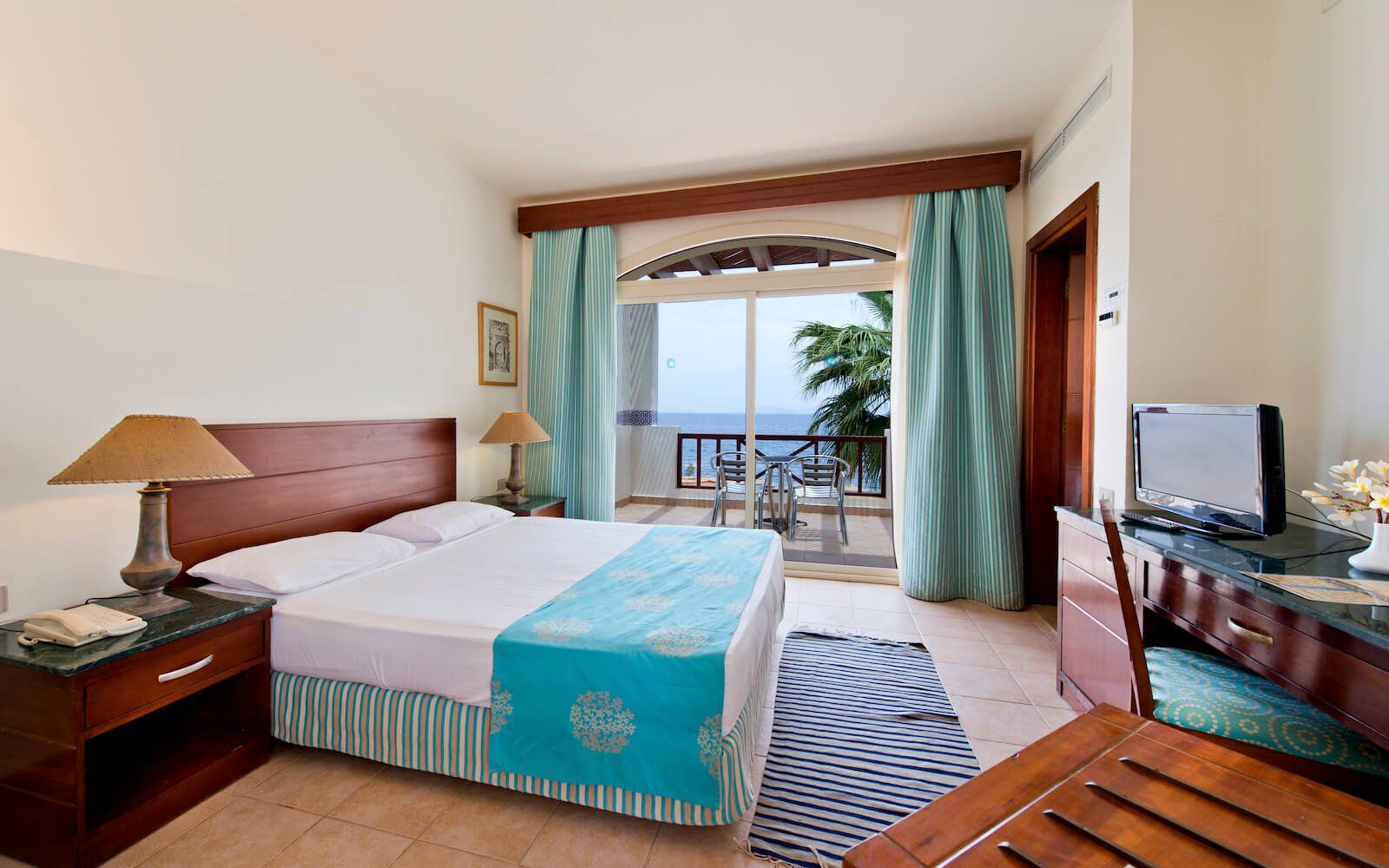 Comfortable hotel room with king-size bed, cozy decor, and balcony view.