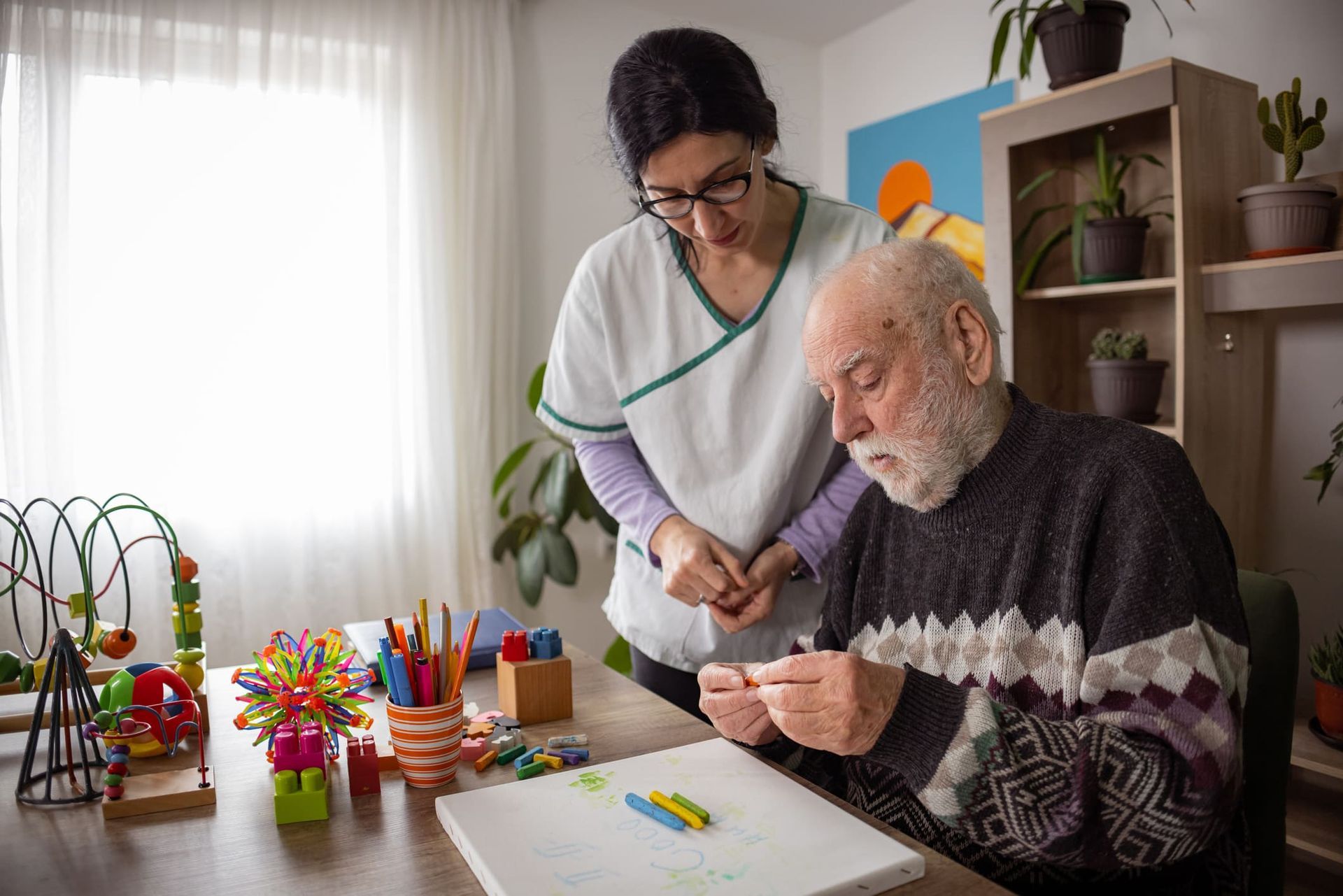 An elderly man is sitting at a table with a nurse.