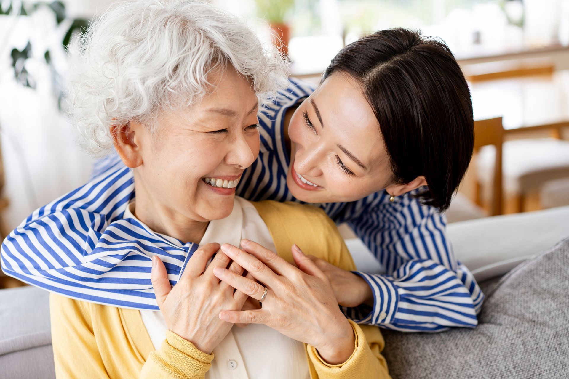 A young woman is hugging an older woman on a couch.