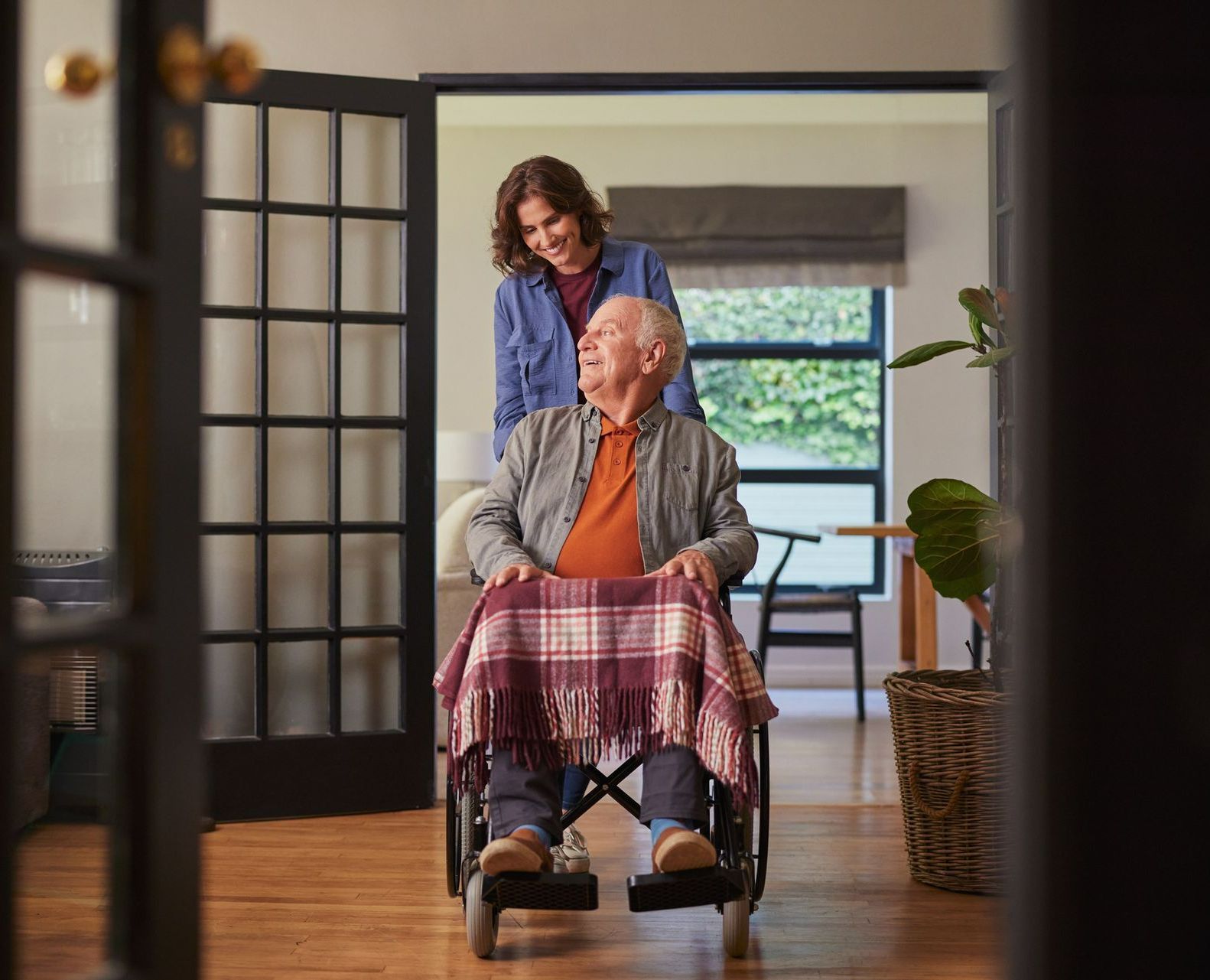 A woman in blue is pushing a man in a wheelchair