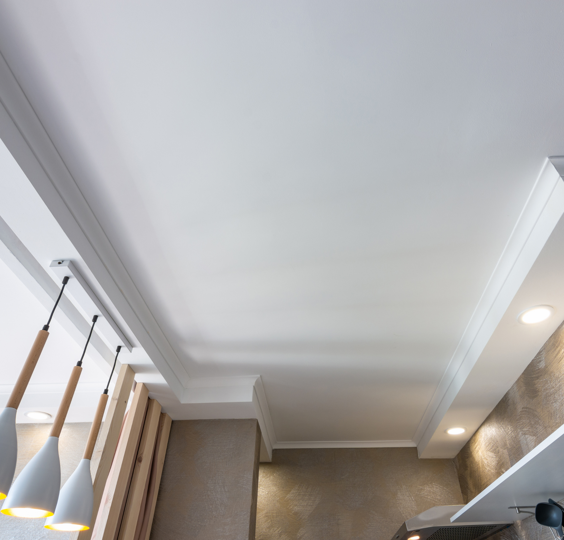 A kitchen with a white ceiling and hanging lights