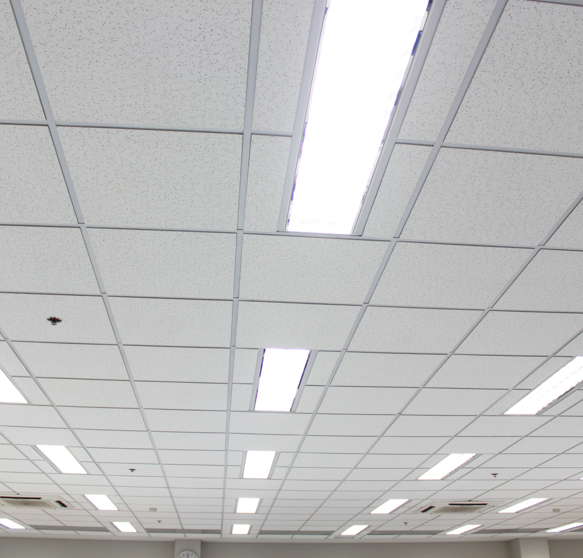 A white tiled ceiling with a few lights on it