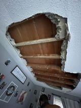 a person is standing in a room with a hole in the ceiling .